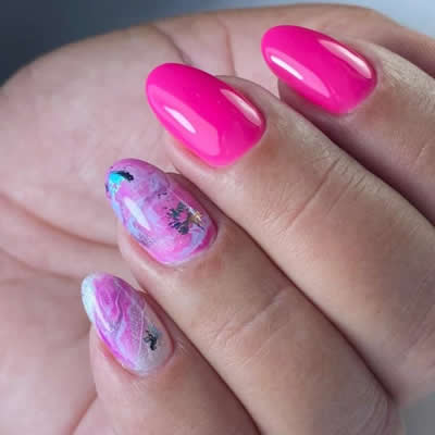 MANO UÑAS PINTADAS DE TONOS ROSA CON DISEÑOS ABSTRACTOS