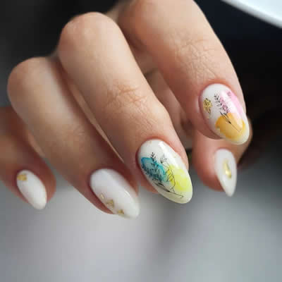 MANO UÑAS PINTADAS DE COLORES AMARILLO, AZUL Y BLANCO CON DISEÑOS FLORALES