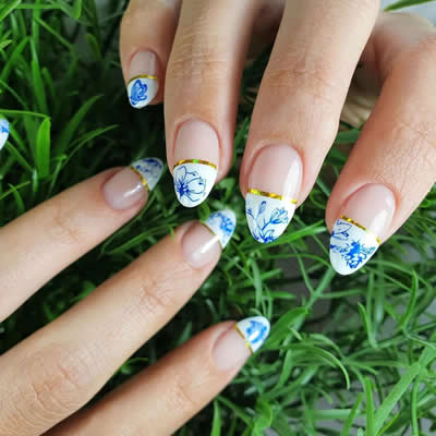 MANO UÑAS PINTADAS DE COLORES AZUL Y BLANCO CON DISEÑOS FLORALES